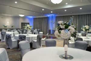 a banquet hall with white tables and chairs and flowers at Delta Hotels by Marriott Waltham Abbey in Waltham Abbey