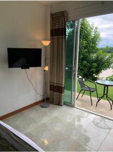 a living room with a television and a patio with a table at Chiang Khan Riverside Bungalows in Chiang Khan
