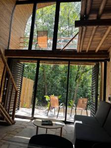 パレンケにあるCabaña de Bambú en la Selvaのリビングルーム(大きな窓、椅子、テーブル付)