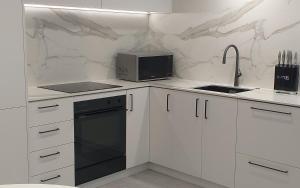 a white kitchen with a sink and a microwave at Apartment Twelve in Taupo