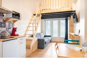 salon z kanapą i łóżkiem na podwyższeniu w obiekcie Villa des palmiers, Studio cosy w mieście Villeneuve-sur-Lot