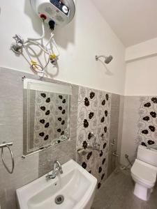 La salle de bains est pourvue d'un lavabo, de toilettes et d'un miroir. dans l'établissement Hotel Mansarovar Inn, à Munsyari