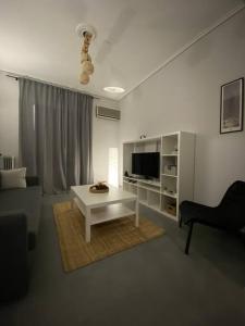 ein Wohnzimmer mit einem weißen Tisch und einem TV in der Unterkunft Elia's boutique apartment in Sparta