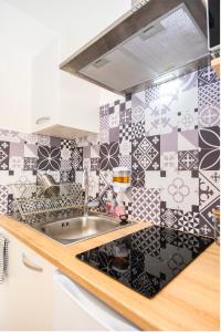 a kitchen with black and white tile on the wall at Villa des palmiers, Studio cosy in Villeneuve-sur-Lot