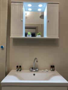 ein Waschbecken im Badezimmer mit Spiegel und Waschbecken sidx sidx sidx in der Unterkunft Elia's boutique apartment in Sparta
