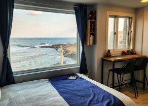 a bedroom with a window with a view of the ocean at Sometimes Jeju in Jeju