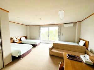 a hotel room with two beds and a couch at 森林公園スイス村 風のがっこう京都 in Kyotango