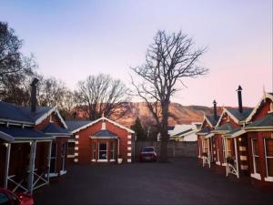 una fila de casas con montañas en el fondo en Tom's Place Guest House, en Harrismith