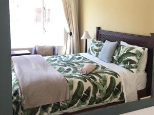 a bedroom with a bed with a green and white blanket at Tom's Place Guest House in Harrismith
