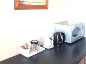 a counter with a coffee maker and a microwave at Tom's Place Guest House in Harrismith