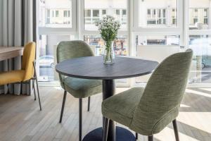 uma mesa com cadeiras e um vaso de flores sobre ela em numa I Blend Apartments em Munique