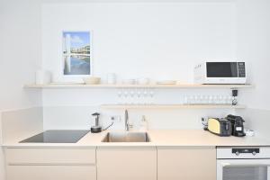eine weiße Küche mit einer Spüle und einer Mikrowelle in der Unterkunft The Levana 3BR Duplex Penthouse by HolyGuest in Tel Aviv