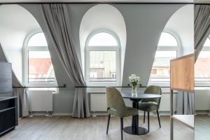 uma sala de jantar com janelas arqueadas e uma mesa e cadeiras em numa I Blend Apartments em Munique
