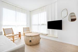 ein weißes Wohnzimmer mit einem Fass-Couchtisch in der Unterkunft The Levana 3BR Duplex Penthouse by HolyGuest in Tel Aviv