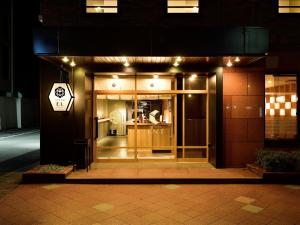 a building with a glass door at night at Hotel Elcient Kyoto Hachijoguchi in Kyoto