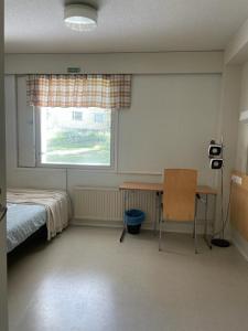 a bedroom with a bed and a desk and a window at Voionmajoitus Soihtu in Ylöjärvi
