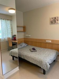 a bedroom with a bed with a mirror and a table at Voionmajoitus Soihtu in Ylöjärvi