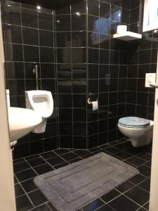 a black tiled bathroom with a toilet and a sink at Deep City Vienna in Vienna