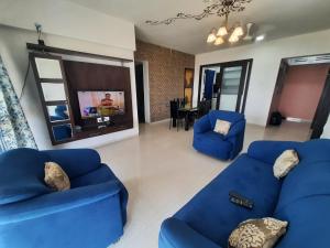 uma sala de estar com dois sofás azuis e uma televisão em Staeg Skyline View 3BHK - 1404 em Indore