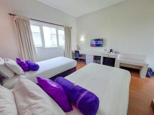 Habitación de hotel con 2 camas con almohadas moradas en HOTEL TILAMAS, en Dares