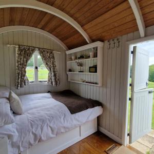1 dormitorio con cama y techo de madera en Molly Dishwasher Shepherds Hut en Frant