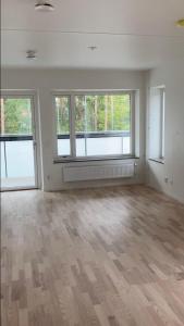 una sala de estar vacía con 2 ventanas y suelo de madera en Cozy Room en Borås