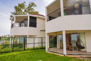 a white house with a balcony and a yard at Summer House Resort in Yercaud
