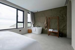 um quarto com uma banheira e uma grande janela em Dengguan Seaview Villa Designer Homestay -Zhoushan Putuo Baisha Island Branch em Zhoushan