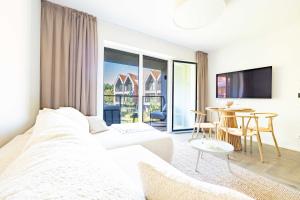 a white bedroom with a large bed and a dining room at Baltic Pine Retreat W/Balcony, By Cohost in Palanga