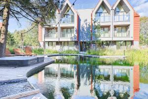 a building with a pond in front of it at Baltic Pine Retreat W/Balcony, By Cohost in Palanga