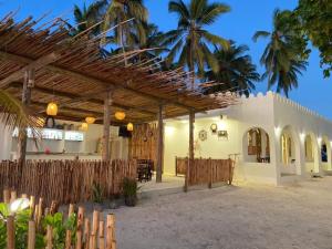 ein Haus mit einem Holzpavillon mit Palmen in der Unterkunft Coco Beach Hotel in Jambiani