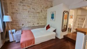 une chambre avec un lit blanc et un mur de briques dans l'établissement Happy Stay Paris - Tournelles Garden, à Paris