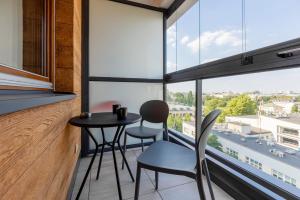 two chairs and a table in a room with large windows at Beautiful Studio with Parking Warsaw Grzybowska by Renters in Warsaw