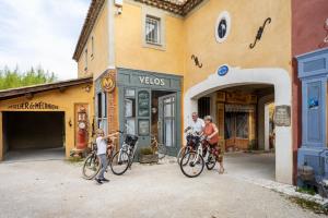 Les TailladesLe Gite Jaune de BelAir的一群人站在一座建筑前面,骑着自行车