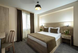 ein Hotelzimmer mit einem großen Bett und einem Stuhl in der Unterkunft Alpina Resort by Stellar Hotels, Tsaghkadzor in Zaghkadsor