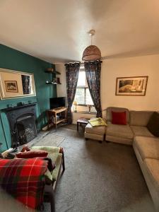 Kasbah cosy cottage Kendal في كندال: غرفة معيشة مع أريكة ومدفأة
