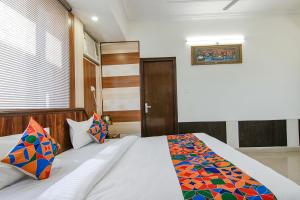 a bedroom with a white bed with colorful sheets and pillows at FabExpress Vistara Grand in Haridwār
