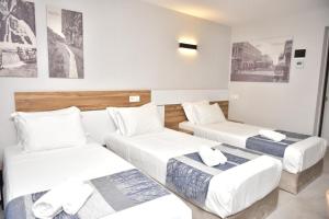 Habitación de hotel con 3 camas y pinturas en la pared en Old Batumi Hotel en Batumi