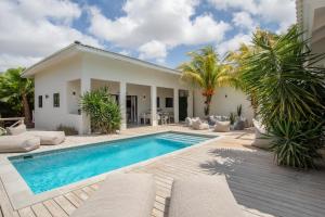 a swimming pool in front of a house at Villa CuraLuna in Jan Thiel