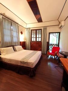 een slaapkamer met een bed en een rode stoel bij Sepilok Jungle Resort in Sepilok