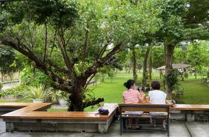 two women sitting on a bench in a park at Family House Zen Boutique Resort in Pai