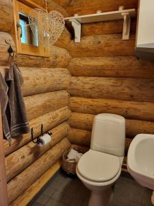 a bathroom with a toilet and a wooden wall at Hirsitalo ja -sauna in Nummi