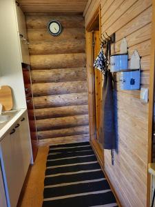 Habitación con reloj en una pared de madera en Hirsitalo ja -sauna en Nummi