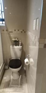 a bathroom with a toilet with a black seat and flowers at VIP Deluxe Restroom Zone in Durban