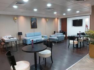 a waiting room with blue couches and tables and chairs at Arabian Hotel Apartments in Ajman 