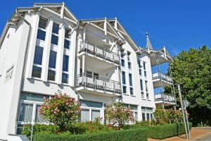 a white building with balconies on a street at Appartementhaus mit Balkon im Ostseebad Göhren HM-10-18 in Göhren