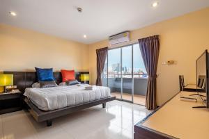 a bedroom with a bed and a desk and a window at TYCOON PLACE Garden 泰坤华裔酒店 in Pattaya South