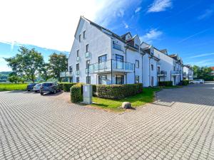 a large white building with cars parked in a parking lot at Haffblick Wohnung 65 in Boltenhagen