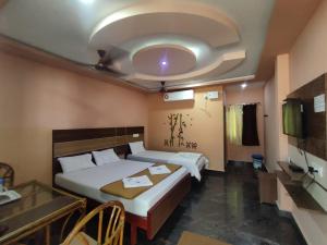 1 dormitorio con 2 camas, mesa y techo en sri Murugan beach paradise hotel, en Mahabalipuram