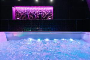LuxeCityApartment في تالين: حوض استحمام مع أضواء أرجوانية في الغرفة